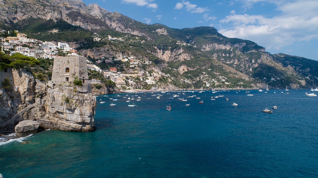 Aerial Italian coastline, turquoise water meeting rocky cliffs